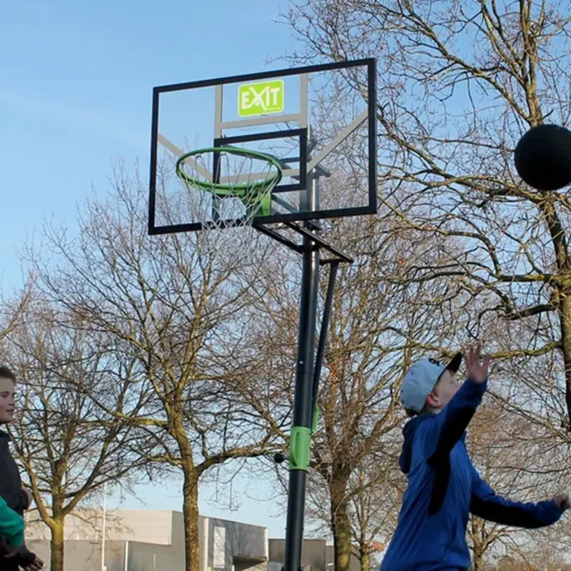 Zwei Kinder spielen Basketball an einem freistehenden EXIT Basketballkorb mit grünem Ring im Freien